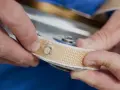 Manos sujetando una cinta de persiana rota, preparándose para cambiarla.