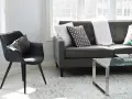 Un sillón negro y un sofá gris con cojines decorativos, listos para aprender como tapizar un sofa y renovar tu sala.