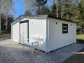 Caseta blanca con puerta doble y ventana, ideal para hacer caseta con palets. Un banco blanco invita a sentarse.