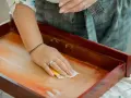 Mano limpiando un cajón de madera antiguo con un paño. Un paso esencial para saber como limpiar muebles de madera antiguos.