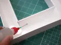 Aplicando adhesivo con precisión para saber como pegar el metacrilato y unir las piezas de forma segura.