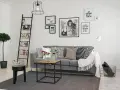 Ideas para combinar cuadros en la pared: un salón moderno con sofá gris, escalera decorativa y arte gráfico.