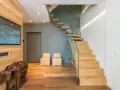 Moderna entrada con una impresionante escalera de madera flotante.