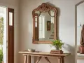 Entrada con puerta doble de madera, espejo ornamentado y consola rústica. Dicen que es malo tener un espejo frente a la puerta, pero este refleja la luz y el exterior.