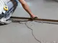 Obrero trabajando para hacer suelo de cemento sobre tierra, alisando la superficie con una llana.