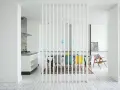 Elegante solución para dividir salón en dos ambientes con un separador de lamas blancas. Cocina moderna y comedor con sillas de colores.