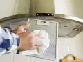 Limpiando el filtro de la campana de acero inoxidable para eliminar huellas y grasa.