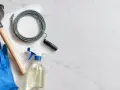 Desatascador, guantes azules, serpentina y spray de limpieza listos para solucionar una tuberia atascada.
