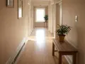 Ideas para como colocar cuadros en un pasillo largo y estrecho: dos cuadros en la pared, una planta y un banco de madera.