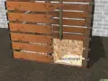 Planos para hacer caseta perro palets. Estructura de madera con entrada arqueada y base cubierta de virutas.