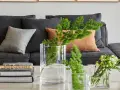 Ideas para decorar mesa de centro rectangular: jarrones con ramas verdes y flores, junto a libros apilados.