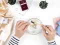 Manos limpian una cadena de oro con un cepillo en agua jabonosa. Aprende como limpiar el oro para que brille como nuevo.