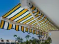 Toldo a rayas amarillas, blancas y azules, un techo corredizo casero perfecto para disfrutar del sol.