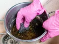 Manos con guantes rosas frotando una olla quemada con estropajo. Un reto para saber como quitar el quemado de una olla.