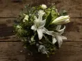 Un ramo de lirios blancos y rosas sobre madera rústica. La pregunta de cuanto dura un ramo de flores depende de su cuidado.