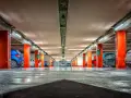 Pasillo de garaje con pilares naranjas y coches aparcados. La imagen evoca la sensación de tener una licencia para garaje particular, un espacio seguro para tu vehículo.