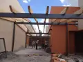 Trabajadores construyen la estructura de un garaje, instalando vigas de metal y madera.