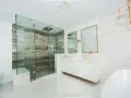 Elegante baño moderno con ducha de cristal, lavabos sobre encimera y detalles dorados. Ideas para decorar un baño de lujo.