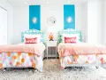 Dos camas gemelas en habitaciones pequeñas, decoradas con cojines que dicen "smile" y ropa de cama colorida.