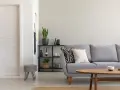 Un salón moderno con sofá gris, mesa de centro de madera y puerta blanca. El suelo claro ayuda a combinar suelo y puertas, creando un espacio luminoso.