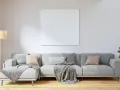 Sofá gris con cojines en tonos tierra y grises, mantas y planta verde. Ideas para combinar cojines con sofá gris.