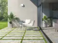 Terrazas pequeñas con encanto: un camino de baldosas y césped lleva a una mesa y sillas blancas, con plantas y un jardín verde.