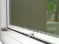 Detalle de mosquitera en ventana blanca. Aprende cómo limpiar mosquiteras para un hogar impecable.