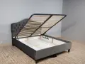 Cama canapé gris con somier abatible, ideal para almacenar.