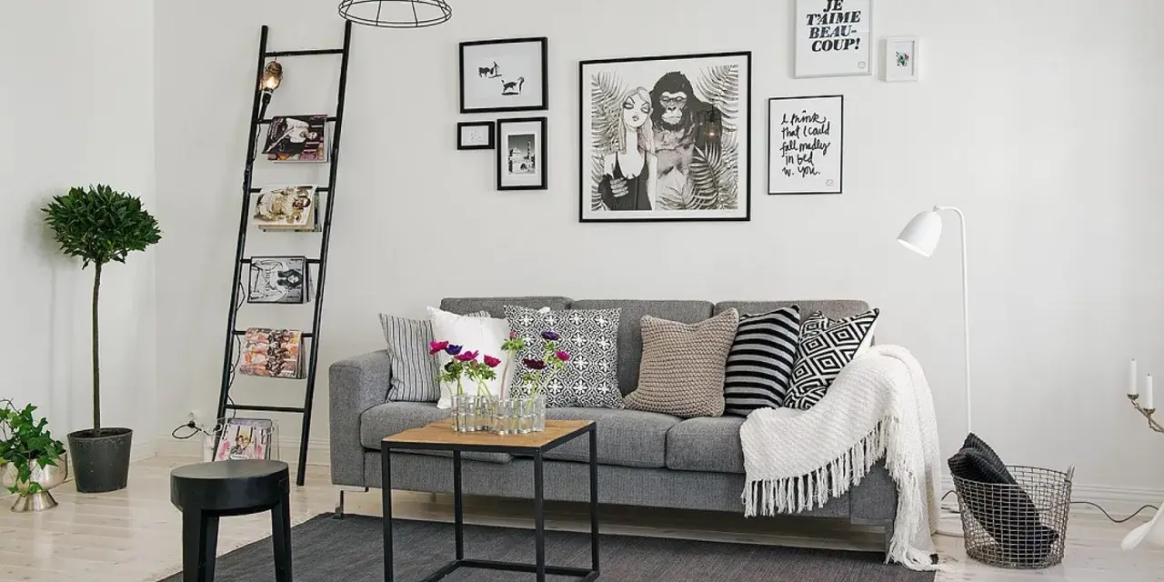 Ideas para combinar cuadros en la pared: un salón moderno con sofá gris, escalera decorativa y arte gráfico.