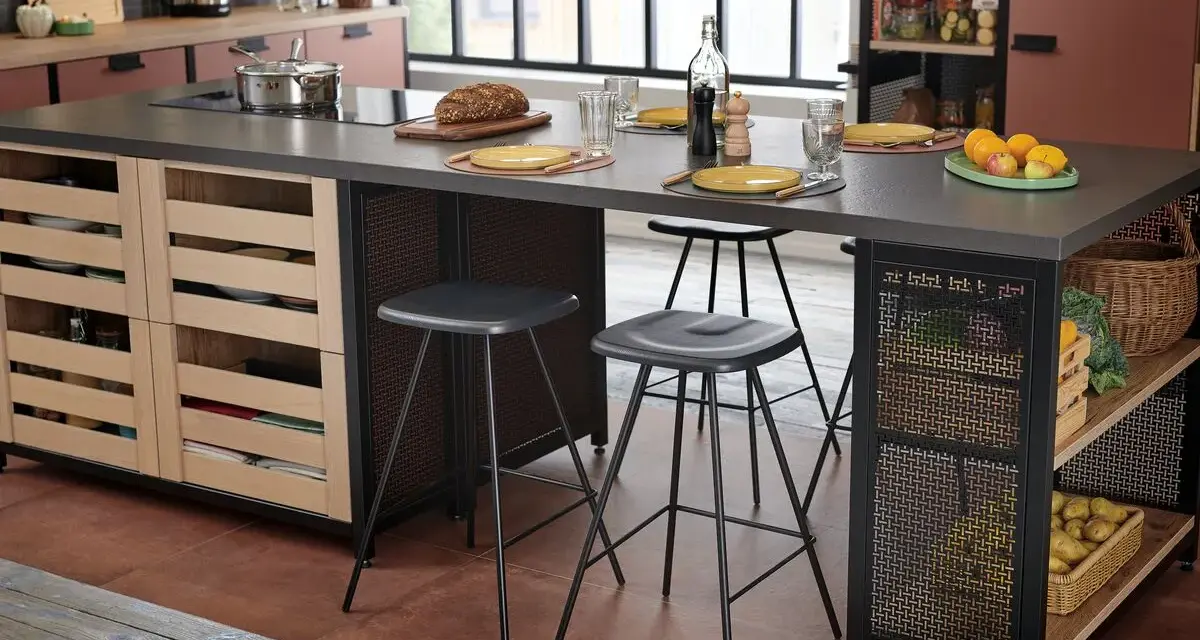 Cocina moderna con isla central y taburetes de altura taburete barra 90. Frutas, pan y vajilla sobre la encimera.