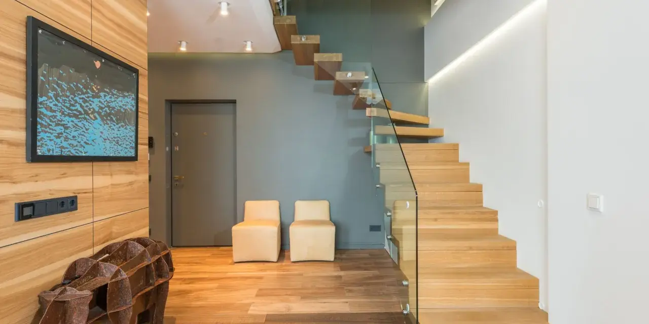 Moderna entrada con una impresionante escalera de madera flotante.