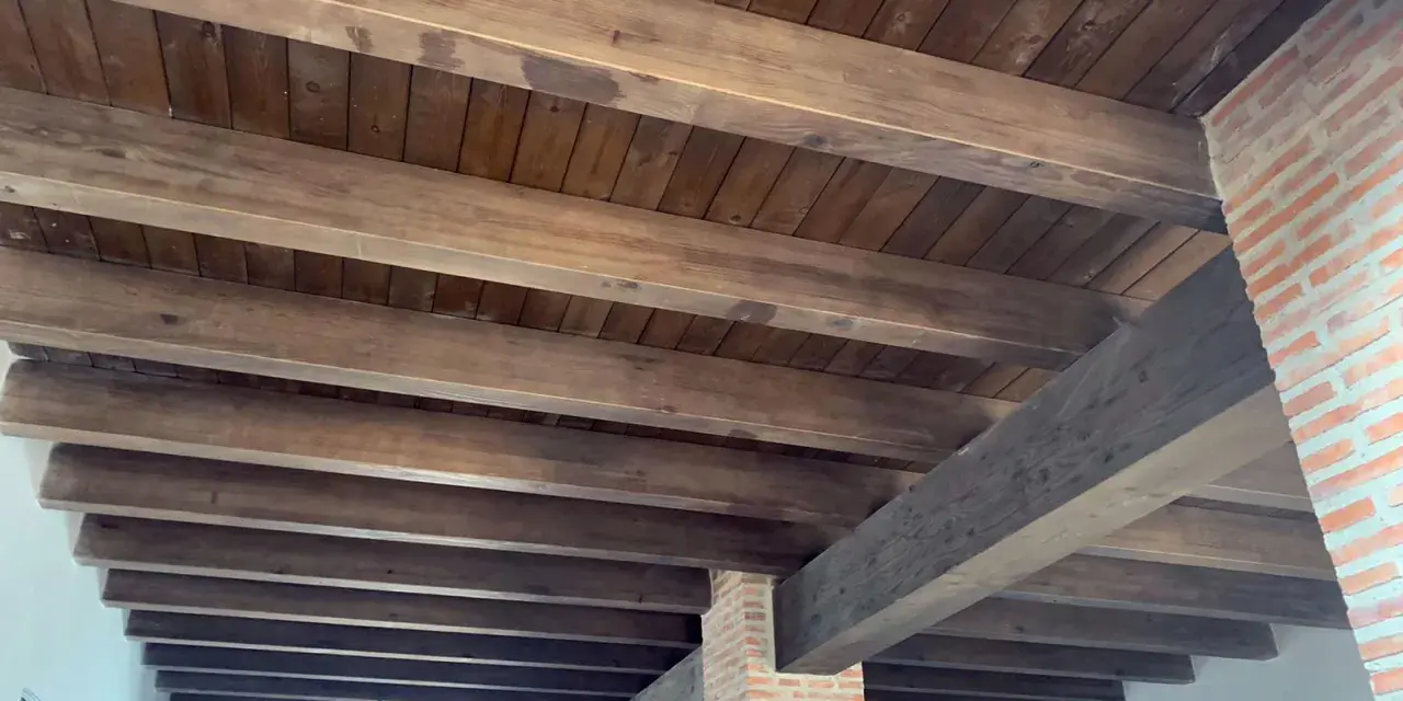 Tejado de madera a un agua con vigas rústicas y entablado oscuro. Ideal para un estilo campestre.