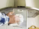Limpiando el filtro de la campana de acero inoxidable para eliminar huellas y grasa.
