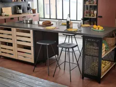 Cocina moderna con isla central y taburetes de altura taburete barra 90. Frutas, pan y vajilla sobre la encimera.