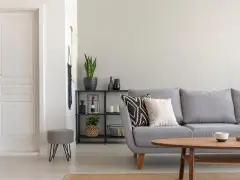 Un salón moderno con sofá gris, mesa de centro de madera y puerta blanca. El suelo claro ayuda a combinar suelo y puertas, creando un espacio luminoso.