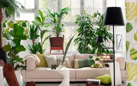 Un salón moderno y luminoso, ideal para decorar con plantas. Un sofá beige, cojines verdes y muchas plantas crean un oasis de frescura.