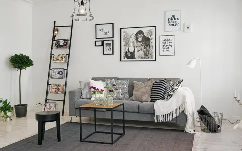 Ideas para combinar cuadros en la pared: un salón moderno con sofá gris, escalera decorativa y arte gráfico.
