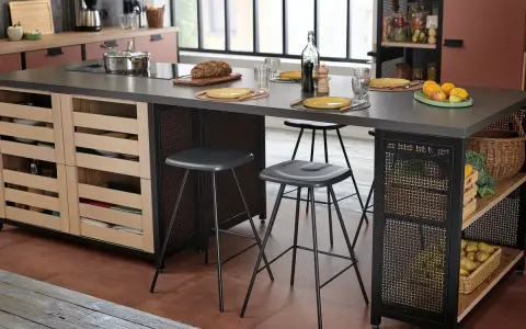 Cocina moderna con isla central y taburetes de altura taburete barra 90. Frutas, pan y vajilla sobre la encimera.