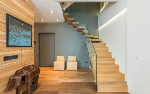 Moderna entrada con una impresionante escalera de madera flotante.