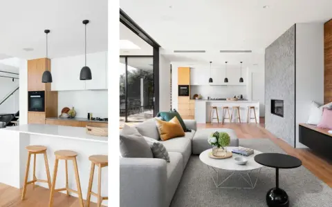 Cocina tipo americana moderna con isla, taburetes de madera y sala de estar contigua con chimenea de piedra.