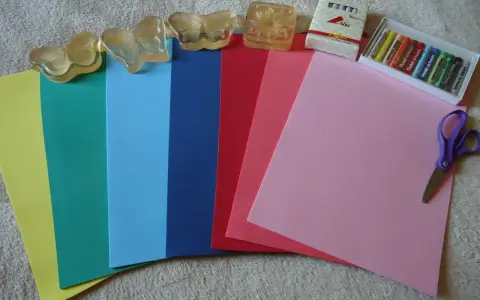 Hojas de goma eva de varios colores, pasteles, tijeras y sellos de mariposa. ¡Ideal para manualidades!
