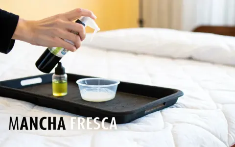 Mano rociando limpiador sobre una bandeja con líquidos para limpiar colchon.