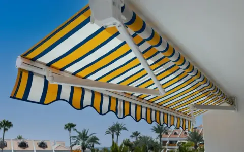 Toldo a rayas amarillas, blancas y azules, un techo corredizo casero perfecto para disfrutar del sol.
