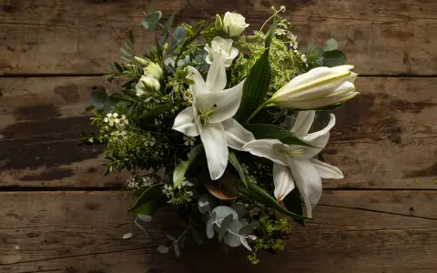 Un ramo de lirios blancos y rosas sobre madera rústica. La pregunta de cuanto dura un ramo de flores depende de su cuidado.