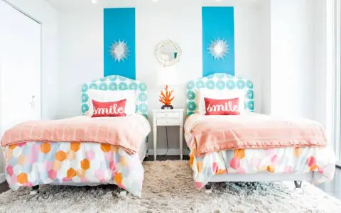 Dos camas gemelas en habitaciones pequeñas, decoradas con cojines que dicen "smile" y ropa de cama colorida.