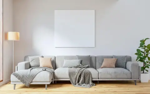 Sofá gris con cojines en tonos tierra y grises, mantas y planta verde. Ideas para combinar cojines con sofá gris.