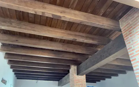Tejado de madera a un agua con vigas rústicas y entablado oscuro. Ideal para un estilo campestre.
