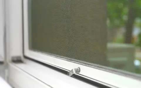Detalle de mosquitera en ventana blanca. Aprende cómo limpiar mosquiteras para un hogar impecable.