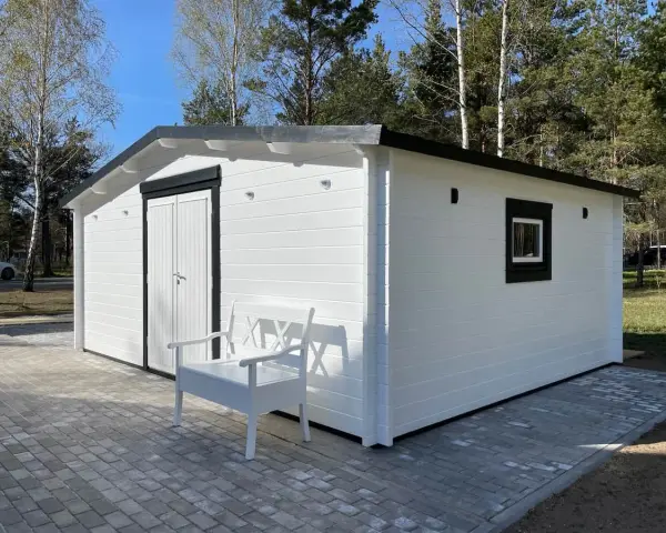 Caseta blanca con puerta doble y ventana, ideal para hacer caseta con palets. Un banco blanco invita a sentarse.