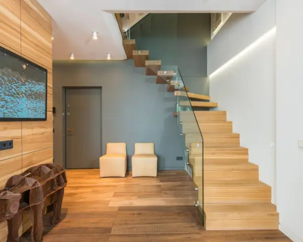 Moderna entrada con una impresionante escalera de madera flotante.